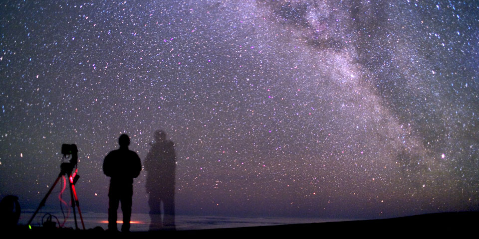 A star filled sky above a person in shadow