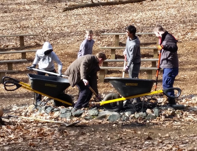 four youth and an adult fix a fire pit