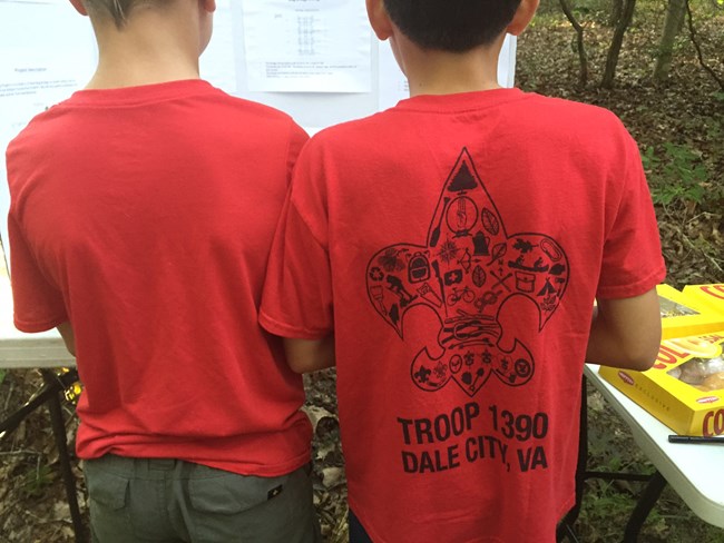 two boy scouts with red tshirts study the plan of work for the day