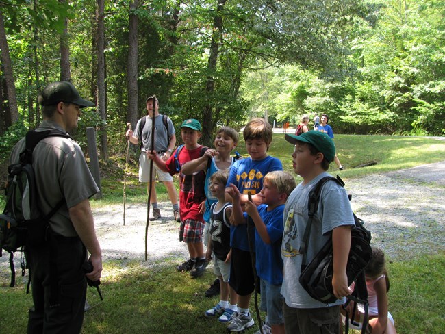 a park ranger and a group of boys wait for the rest of the group to catch up