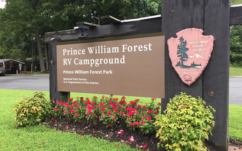 Sign for RV Campground Brown Entrance Sign for Prince William Forest RV Campground surrounded by pink flowers and green grass