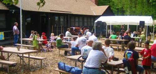 Visitors sitting at picnic tables outside of a cabin