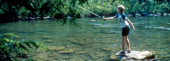 Young boy casting a line into a lake