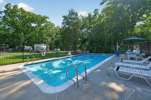 Small blue in ground pool with a fence and lounge chairs in the RV Campground