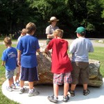 group of kids listening to a ranger program, given by a ranger, standing near a large piece of petrified wood