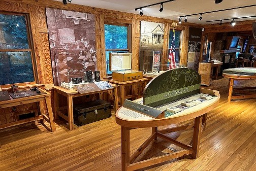 Exhibits on the interior of a wooden visitor center include radio equipment, molds of plants and animals, and a 3D map