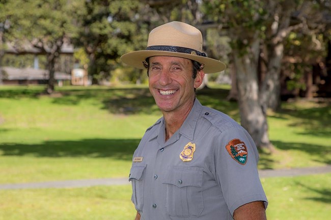 John Broward in NPS uniform smiling and standing in front of a green field