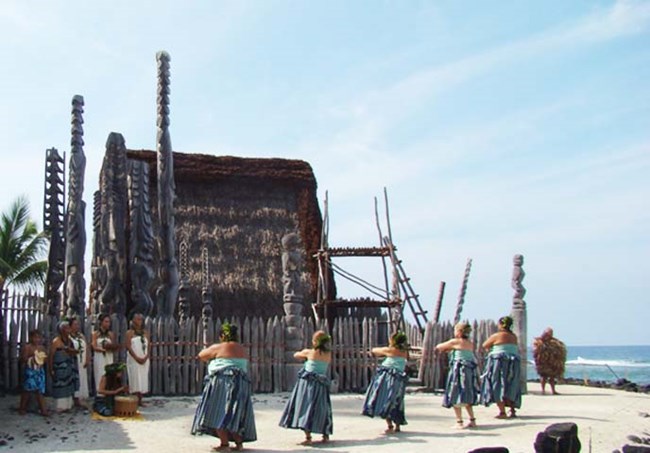 People in traditional clothing perform hula in front of the Hale o Keawe