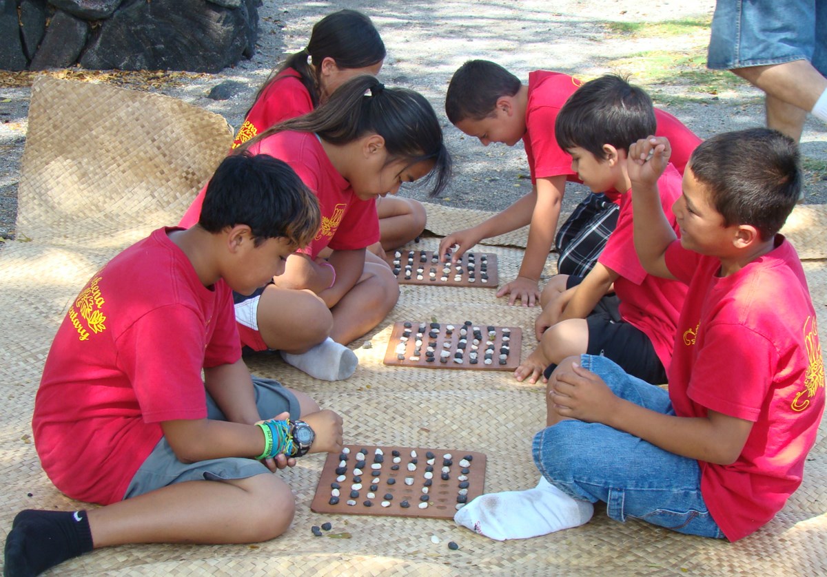 Students learn how to play kōnane (Hawaiian checkers).