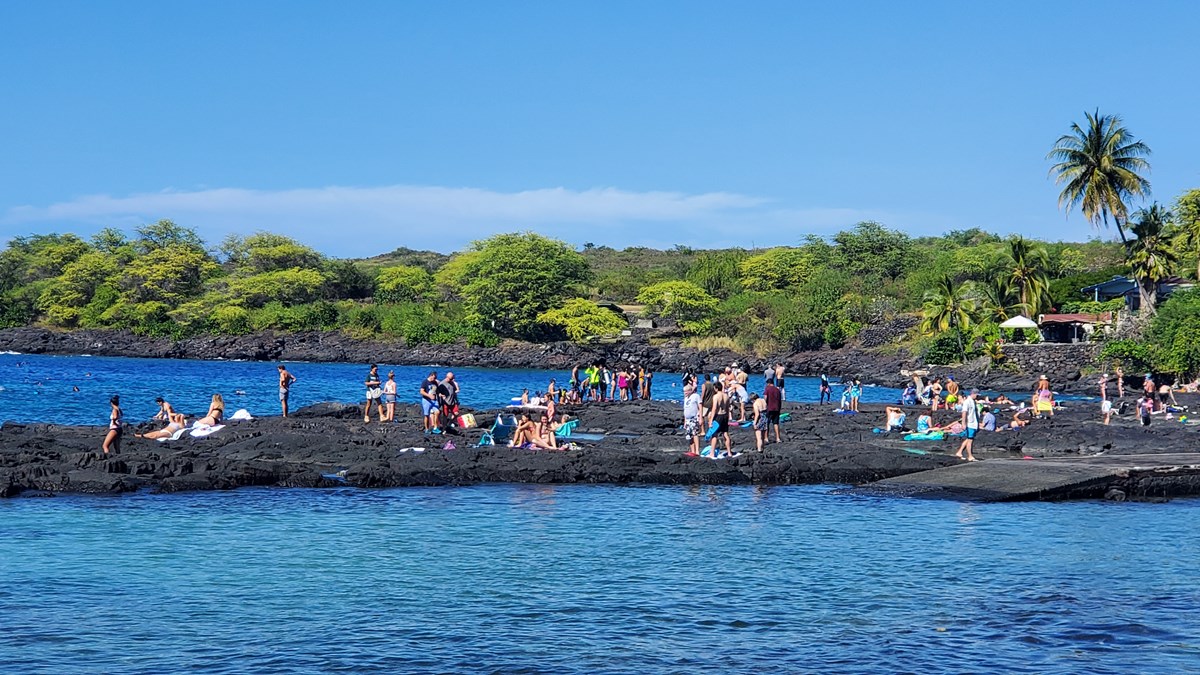 People gather on the lava rock at popular snorkeling spot, "Two Step"