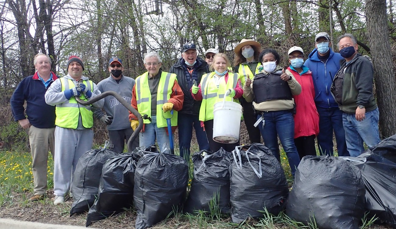 A group of volunteers and a ranger stand in front of a collection of garbage bags.