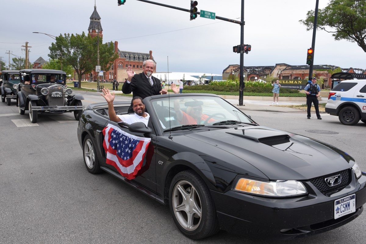 Car Caravan Alderman Anthony Beale, CJ Martello, and Cindy McMahon wave from a flag draped car in front of the Administration Clock Tower Building.
