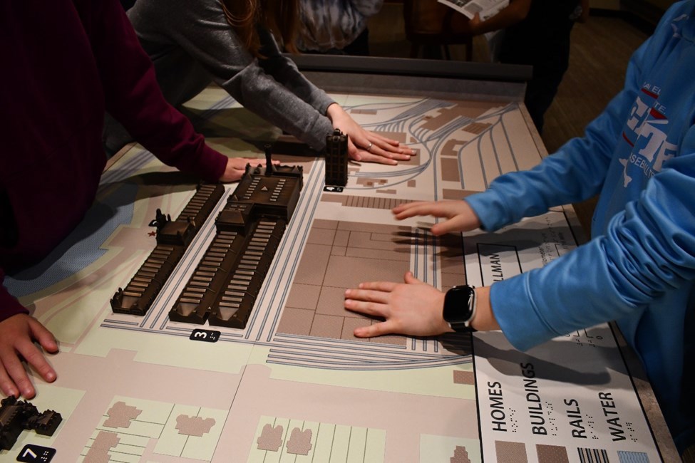 visitor explore a tactile map of Pullman Three visitors explore a tactile bronze and plastic map with their hands