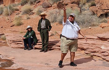 Aramark employee gestures upward while speaking to group near dino track