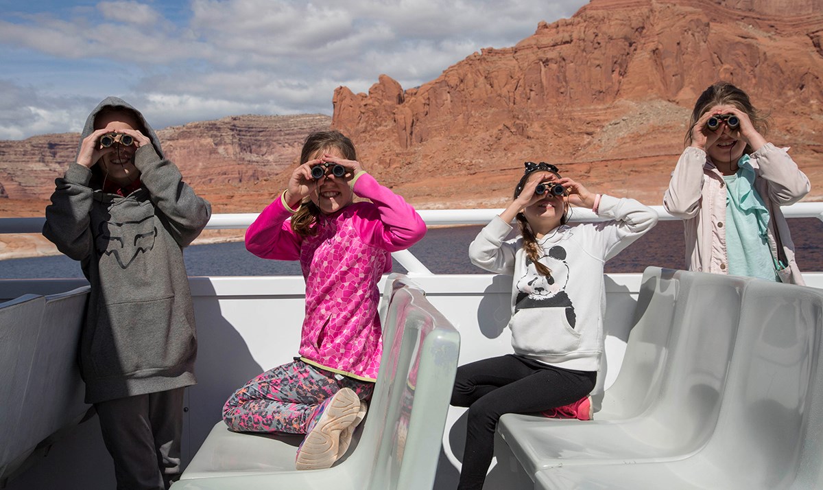 Line of four girls all peering through binoculars