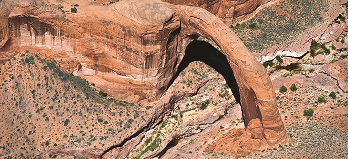 Aerial shot of Rainbow Bridge. a few bushes and rocks underneath.