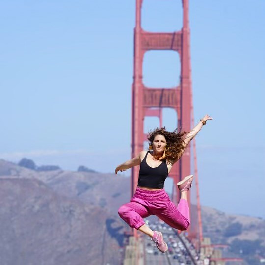 Dance Artist Lauren Godla jumping in midair in front of Golden Gate Bridge.