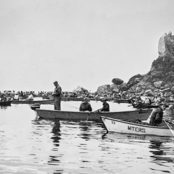 Men fishing from boats, rocks in background