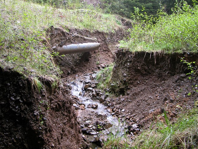 A stream erodes below a failed culvert.