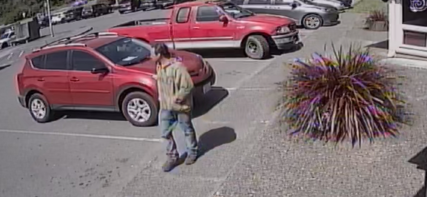 Man with short brown hair wearing jeans, brown hoodie, and brown boots walking in parking lot