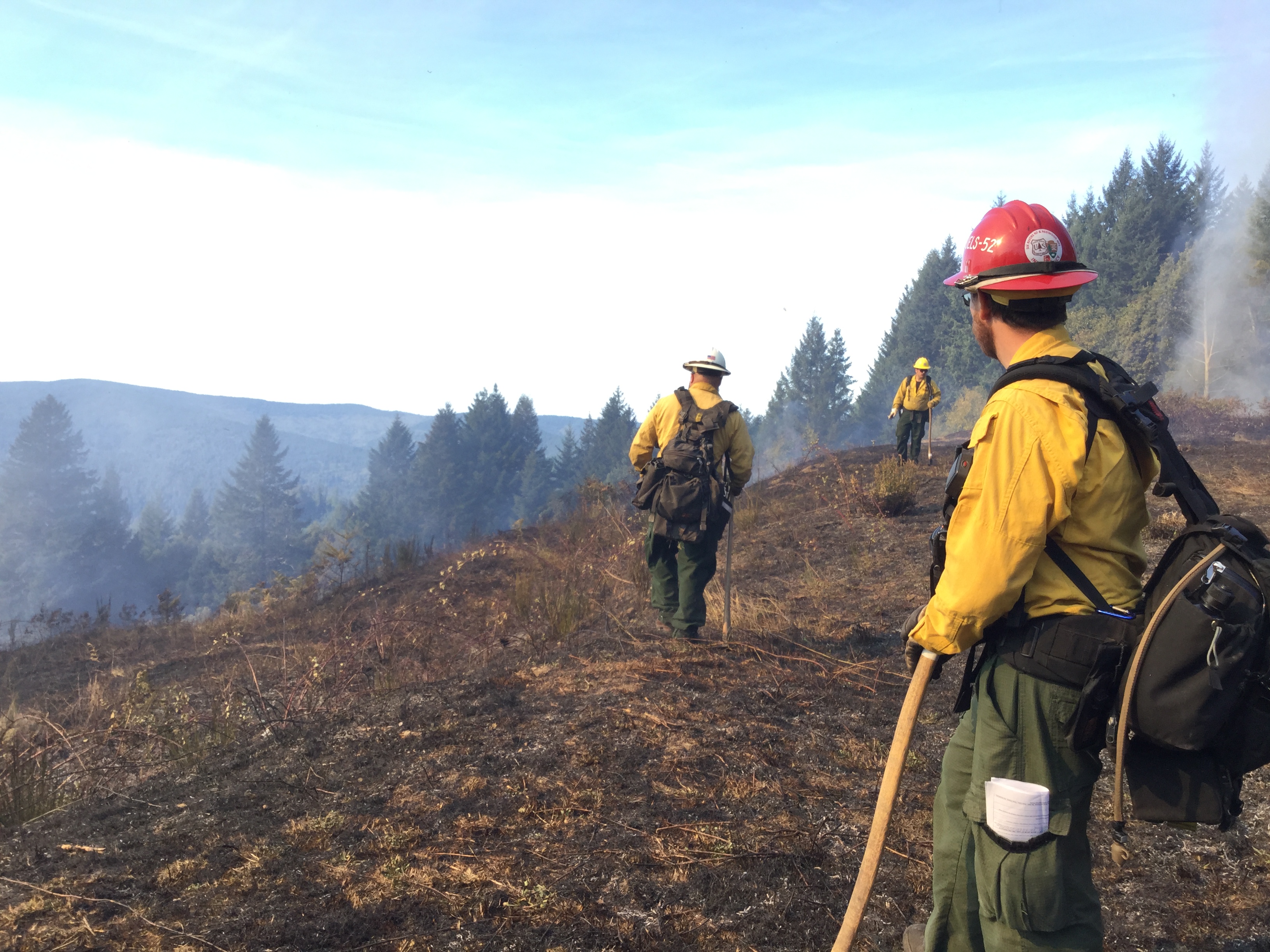 A fire fighter in yellow nomex watches a prescribed fire.