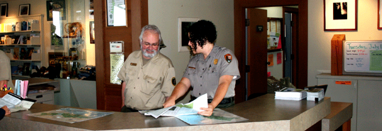 Ranger and uniformed volunteer staff a front desk.