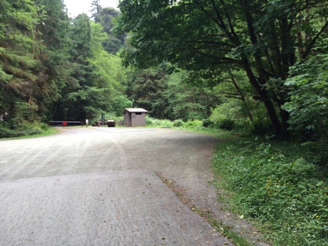 gravel drive with parking area next to a pit toilet