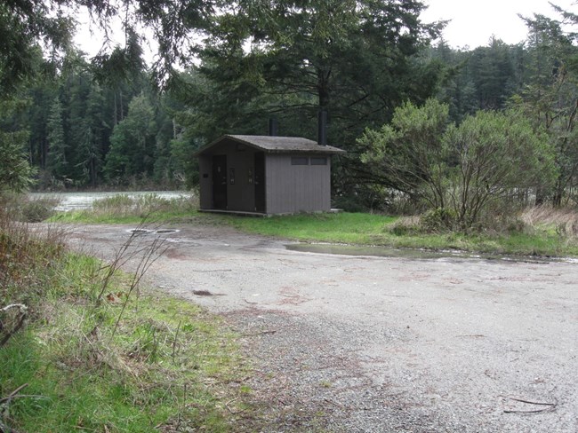 toilet building surrounded by vegetation with Smith River in background
