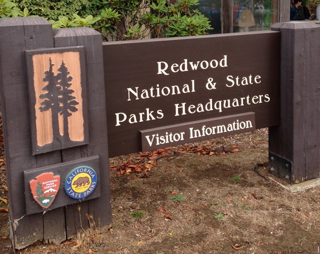 A brown wooden sign says Park Headquarters / Visitor Information
