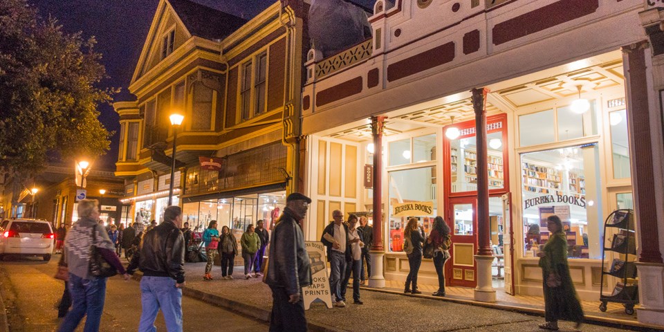 At night, people walk towards historic buildings.