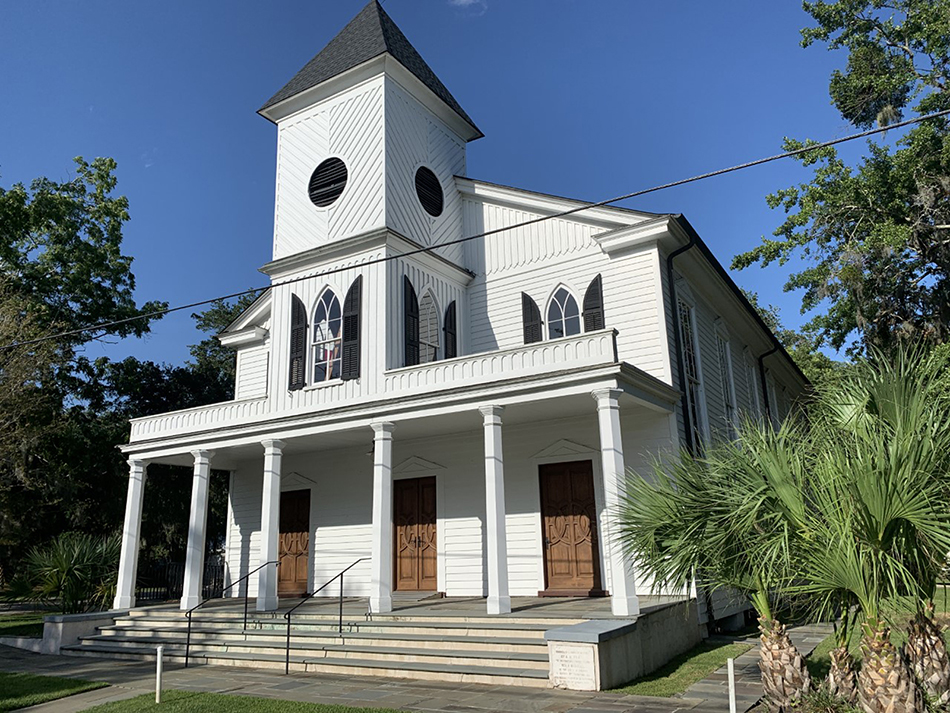 First African Baptist Church in historic downtown Beaufort, South Carolina Wooden Church painted white with a tall wooden steeple, underneath a bright sunny sky