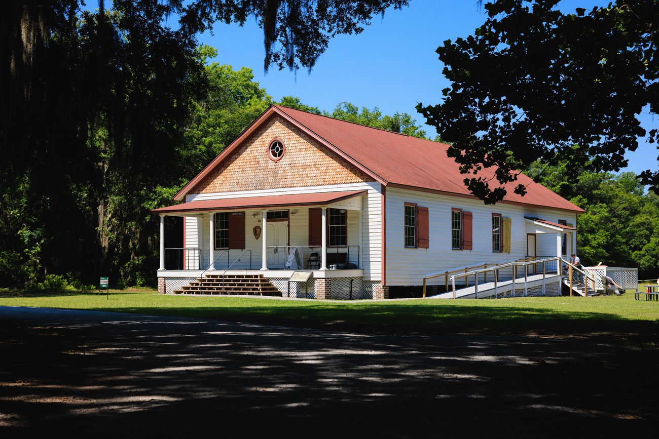 A single-story white building with a porch and red roof.