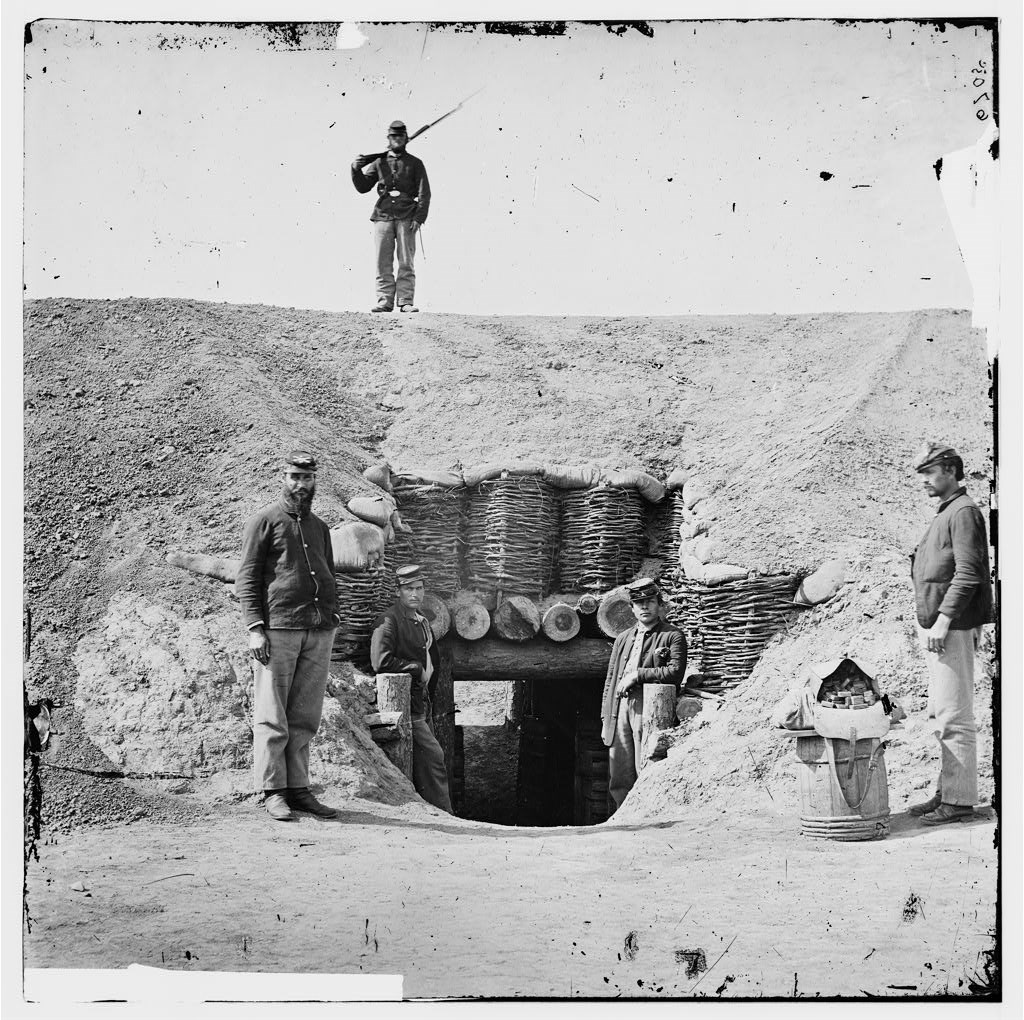 Historic image of four Union soldiers posing at the entrance of the Fort Harrison magazine. Another armed soldier stands on top of the magazine.
