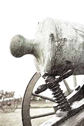 Close up image of the rear of a cannon and the wheel of a cannon carriage in a snow storm.