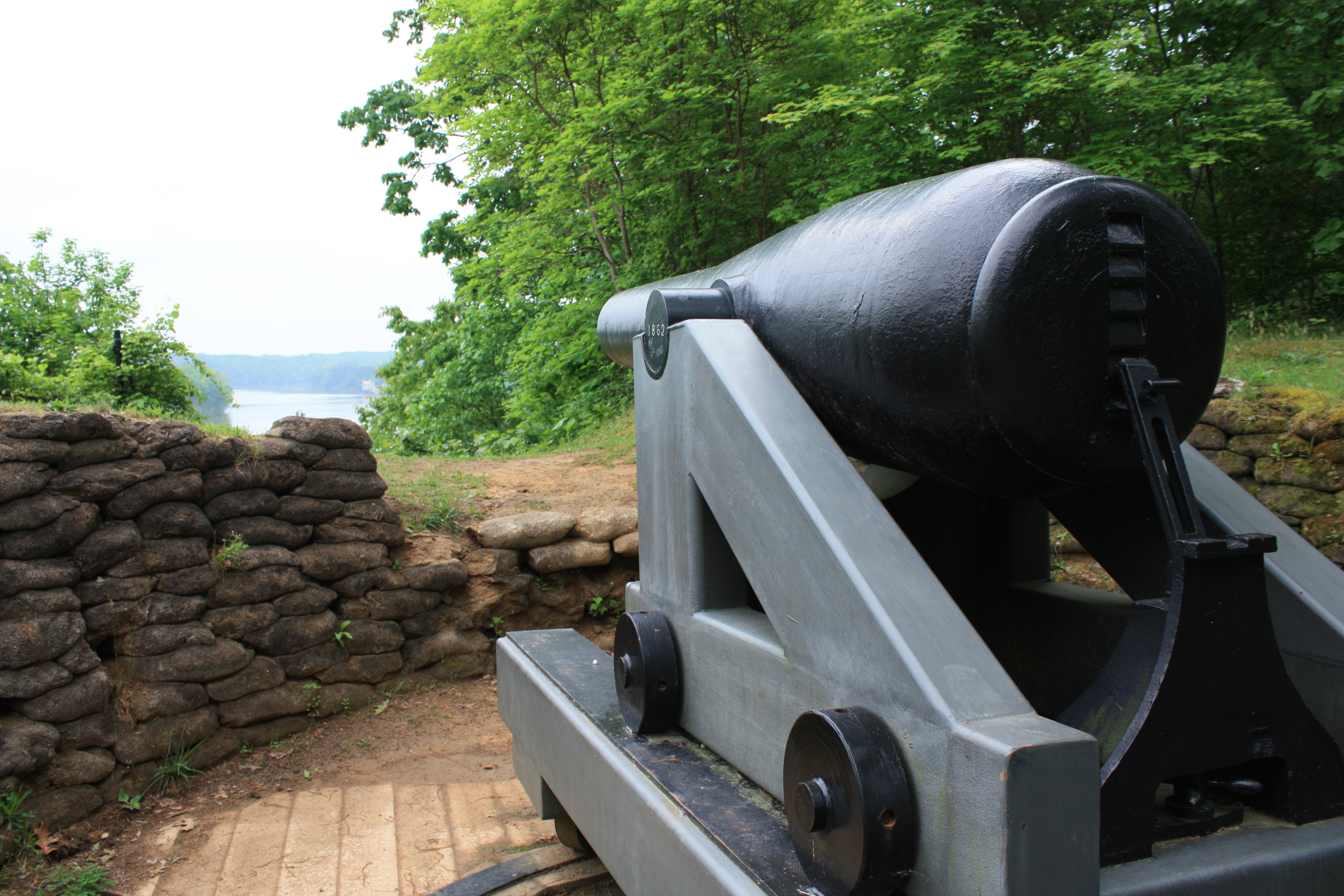 a large black cannon overlooking a river.