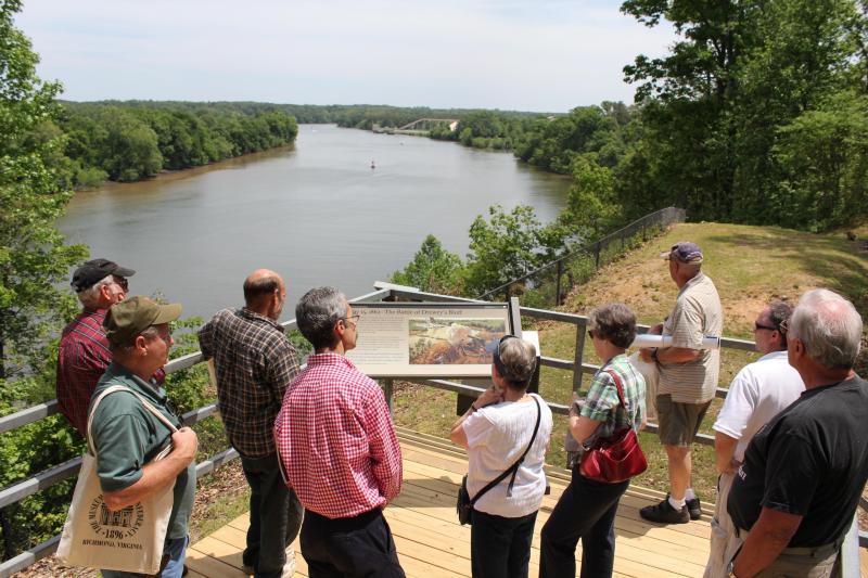 Tour visitors read an interpretive sign overlooking the James River.