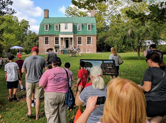 Visitors walk toward a brick plantation house