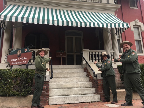 Welcome to Maggie L. Walker National Historic Site! Three park rangers provide a welcoming gesture to the front door of a Victorian row house.
