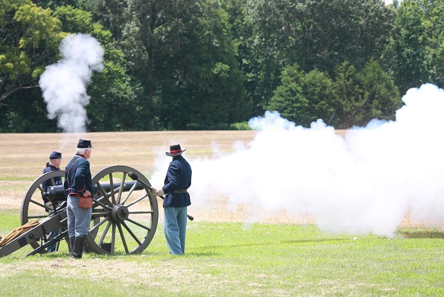 the Battle of Gaines' Mill at Richmond National Battlefield Park Three reenactors in blue civil war uniforms firing a cannon.