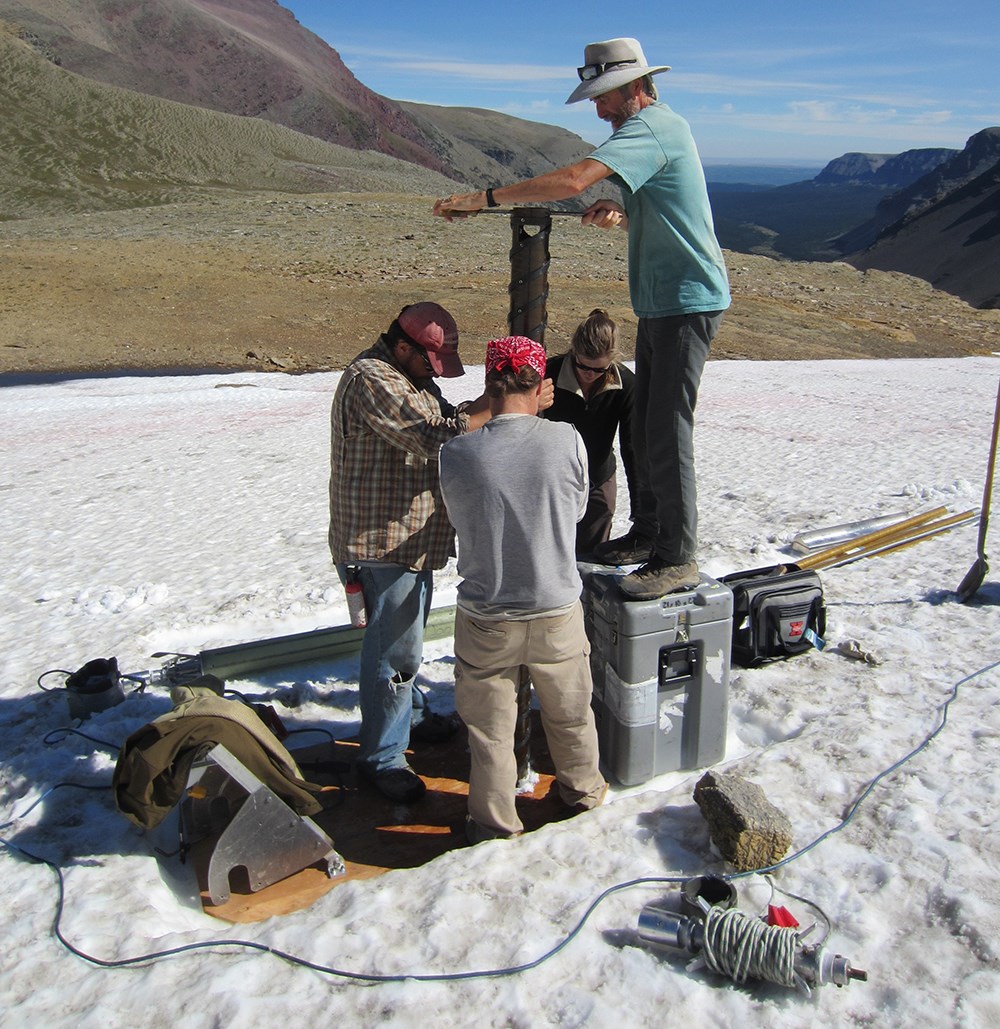 Crew of four uses hand-driven auger on snowfield