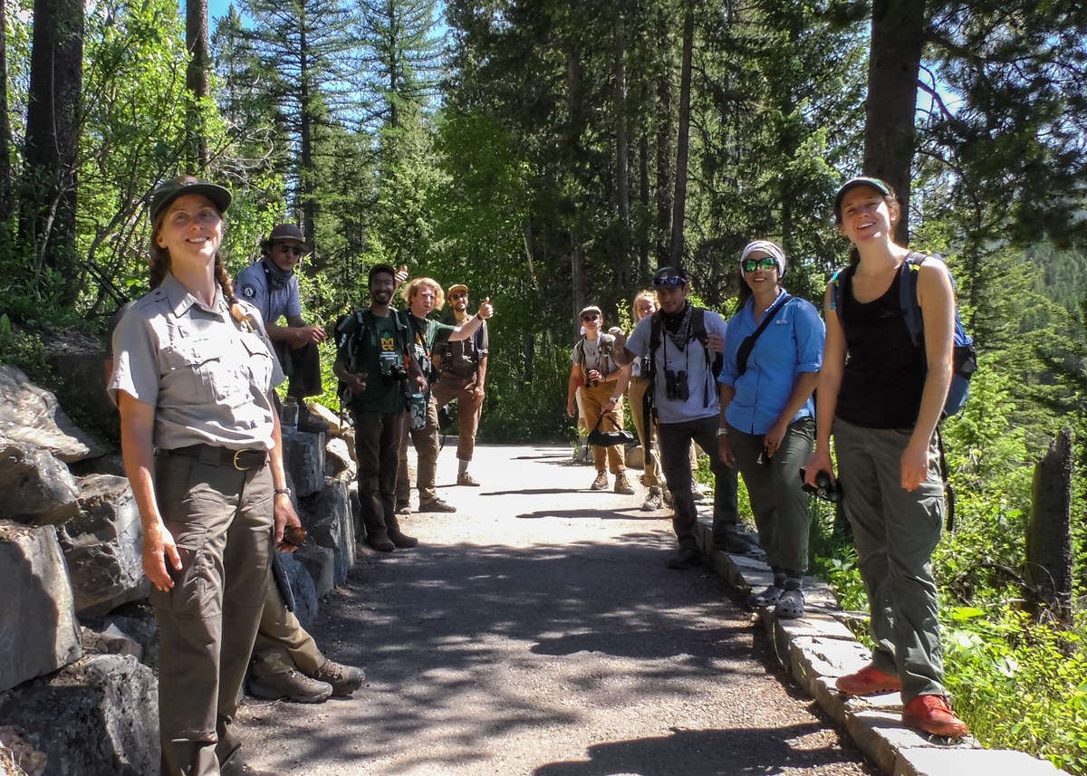 MCC crew and park staff stand lined up on a paved path.