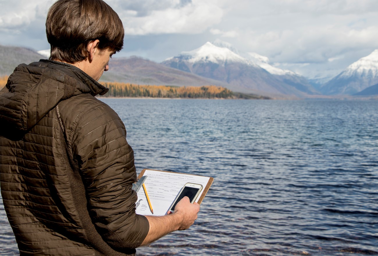 Loon survey app Man holds clipboard with pencil and data sheet and a cell phone.