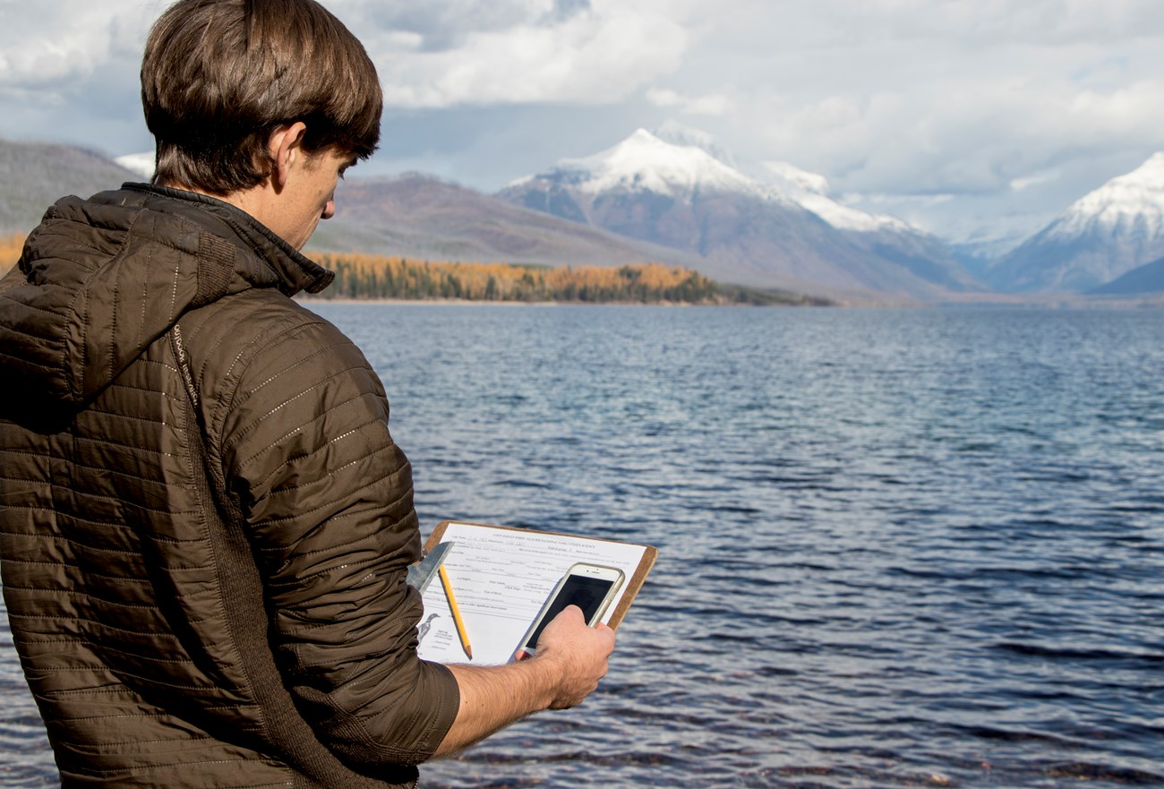 Man holds clipboard with pencil and data sheet and a cell phone.