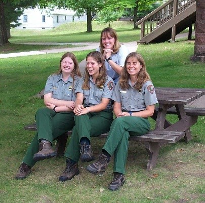 These women look forward to a day of work at Apostle Islands National Lakeshore. Four women in NPS uniforms are sitting on a picnic table.