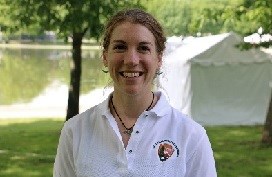 Michelle Verant wears bat jewelry to help people appreciate the beauty and importance of bats. A woman in a National Park Service polo shirt smiles. She is wearing a bat necklace and earrings.