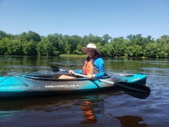 A woman in a blue kayak floats down a river.