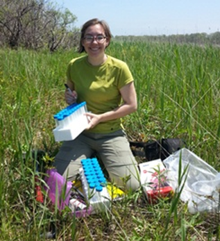 Researcher kneels at the edge of a wetland and prepares equipment for plant sampling. Researcher kneels at the edge of a wetland and prepares equipment for plant sampling.