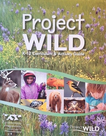 The cover of a book features the words, “Project WILD K-12 Curriculum and Activity Guide”, as well as “Association of Fish and Wildlife Agencies”.  Pictures of wildlife, children, and a prairie are also shown.