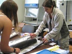 Teacher assists with sediment core sample.