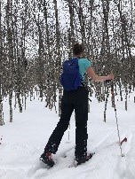 A woman cross country skis down a forest trail.